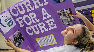 A student holds up a "ݮƵ for a Cure" sign at the Involvement Fair